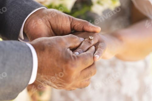 Preview: Hands of senior biracial groom putting wedding ring on finger of his bride