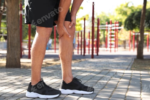 Preview: Man having knee problems on sports ground, closeup