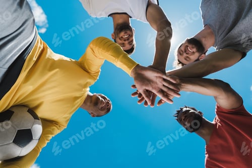 Preview: Bottom view of multiethnic soccer team holding hands together before game
