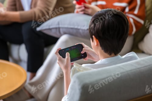 Preview: Boy playing video games on mobile phone.