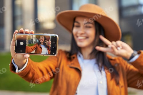 Preview: Happy petty lady taking photo on her smartphone outdoor