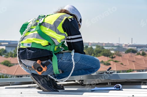 Preview: Male engineer installing or checking the working condition of solar panels on the roof