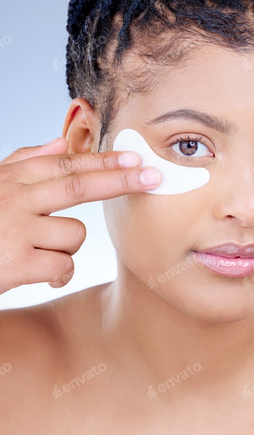Preview: Cropped portrait of an attractive young woman wearing an under eye patch against a blue background