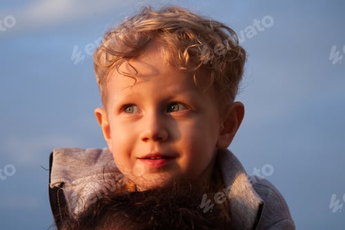 Preview: Portrait of a curly blond boy in the rays of sunset