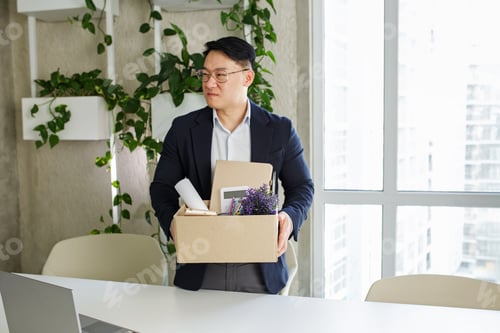 Preview: Firing and job loss concept. An Asian man is fired from job and is packing things into cardboard box