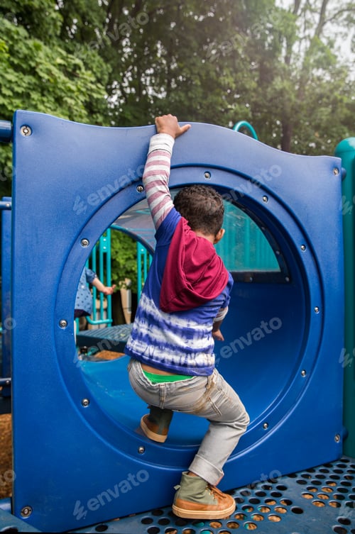 Preview: Rear view of boy climbing playground tunnel