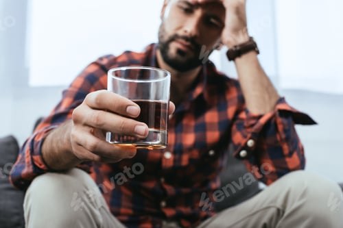 Preview: close-up shot of depressed young man with glass of whiskey