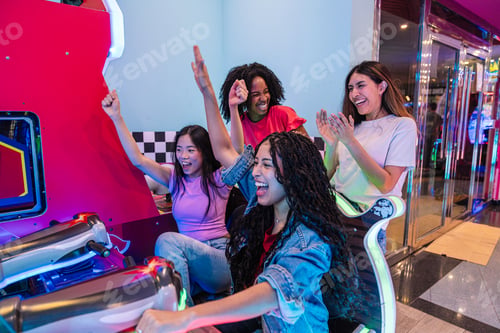 Preview: Excited female friends playing arcade racing game in a bowling alley