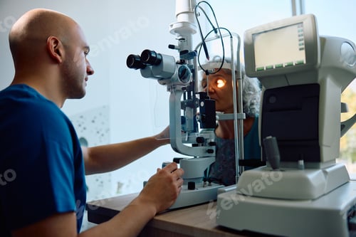 Preview: Ophthalmologist using optical biometer while checking eyesight of senior patient at the clinic.