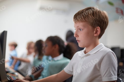 Preview: Focused child engaged in computer class with peers in the background