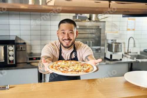 Preview: Smiling Man Presenting Fresh Pizza in Kitchen