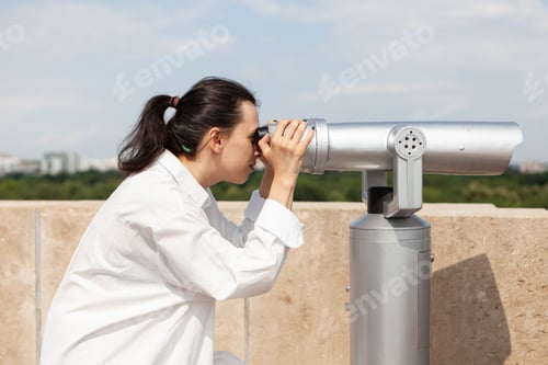 Preview: Caucasian female tourist looking through binoculars telescope