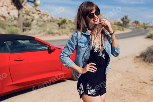 Preview: Sexy traveling woman posing near red sport car