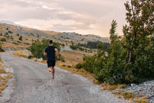 Preview: Determined Athlete Running Through Rugged Mountain Terrain at Sunrise.