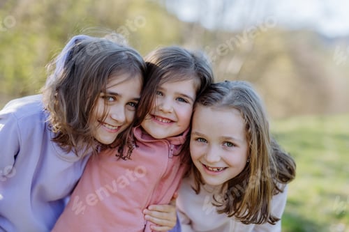 Preview: Three little sisters looking at camera in spring nature together.