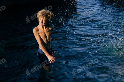 Preview: Boy grimacing in wavy sea with splashing water