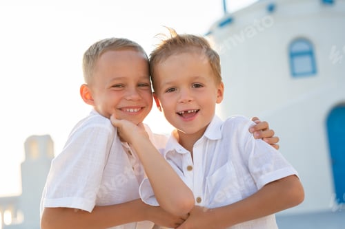 Preview: Portrait of friendly and cheerful brothers at sunset on the island of Santorini, Greece.