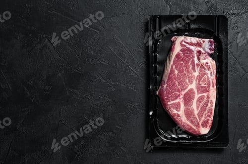Preview: Unopened vacuum pack of pork steak isolated on black background, without label. Black background
