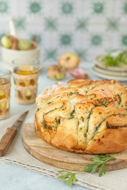 Preview: Freshly baked herb bread on a wooden board with glasses of apple juice and apples in the background.