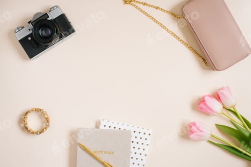 Preview: Notebooks and a bouquet of pink tulip flowers, a bag, a camera. Workplace of a female travel blogger