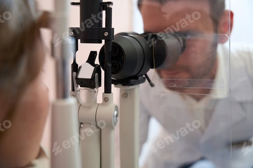 Preview: Ophthalmologist is looking throught the slit lamp in medical center