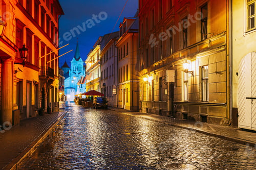Preview: Riga, Latvia. Evening View Of Pils Street With Ancient Architecture In Bright Yellow Illumination