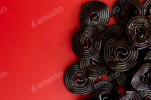 Preview: Flat lay tasty black liquorice candies on red background