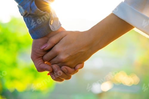 Preview: Close up of young couple joining hands in summer park