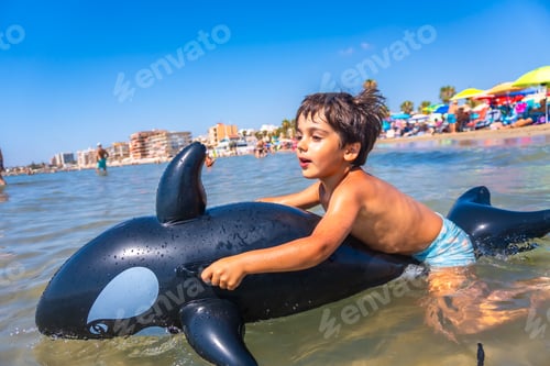 Preview: Child riding inflatable orca at the beach having fun on summer vacation