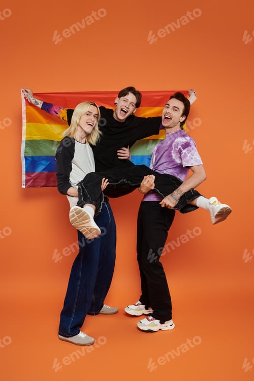 Preview: Queer joy: three friends pose with pride flag