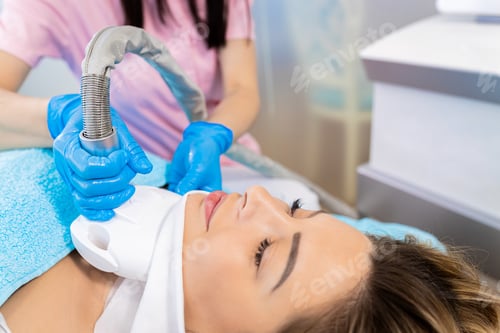Preview: Beautician therapist applying cryolipolysis treatment in beauty salon.