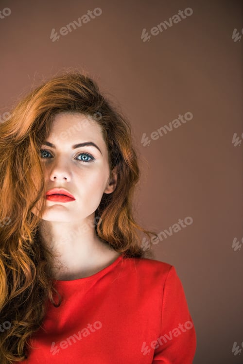 Preview: Woman with long red hair looking at camera isolated on brown background