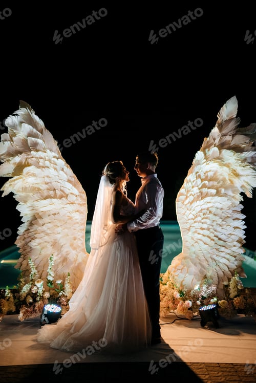 Preview: cutting the wedding cake against the backdrop of white wings