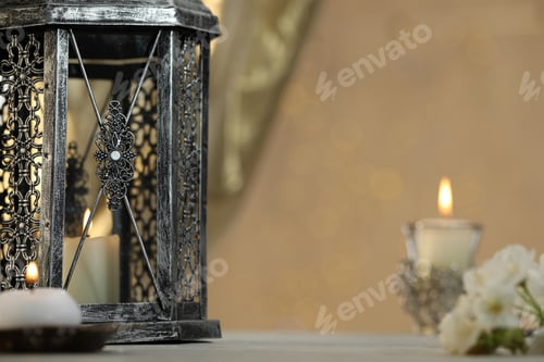 Preview: Arabic lantern and burning candles on table against blurred lights