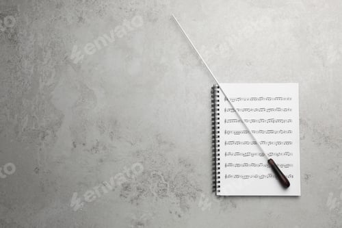 Preview: Conductor's baton and sheet music book on grey background, top view. Space for text