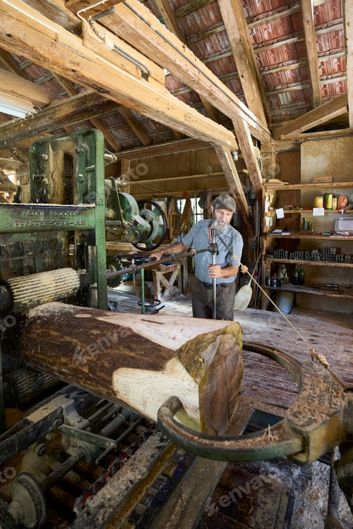 Preview: Piece of a log with sawdust on it and a man working in an old sawmill