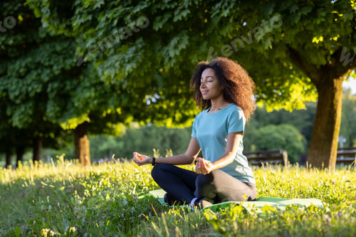 Preview: African American woman practicing yoga meditation in outdoor park setting