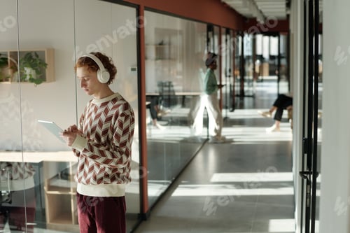 Preview: Young Caucasian Man Using Digital Tablet While Standing in Modern Coworking Space