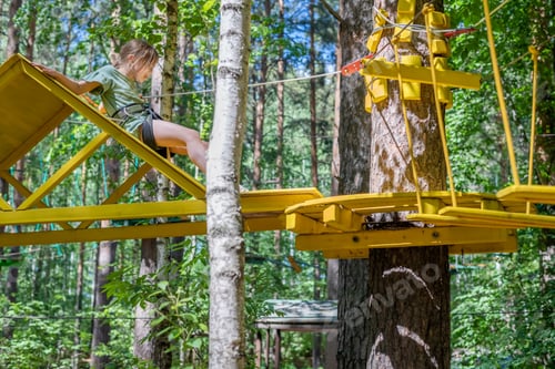 Preview: cute girl in forest adventure park, climb on high rope trail.