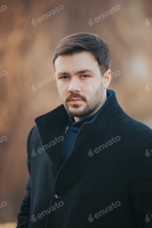 Preview: Vertical shot of an attractive Caucasian male in a jacket posing outdoors
