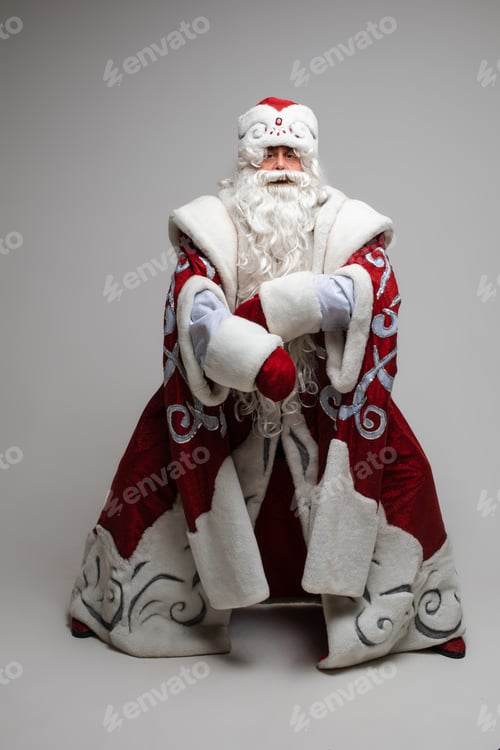 Preview: Cool gray haired with long beard Santa Claus in red clothes posing on gray studio background