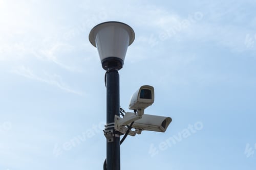 Preview: Surveillance cameras mounted on a lamp post against a blue sky. security cctv camera