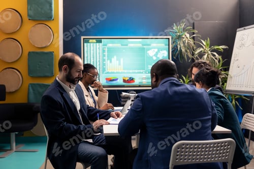 Preview: Business affiliates reviewing sales infographics in a conference room
