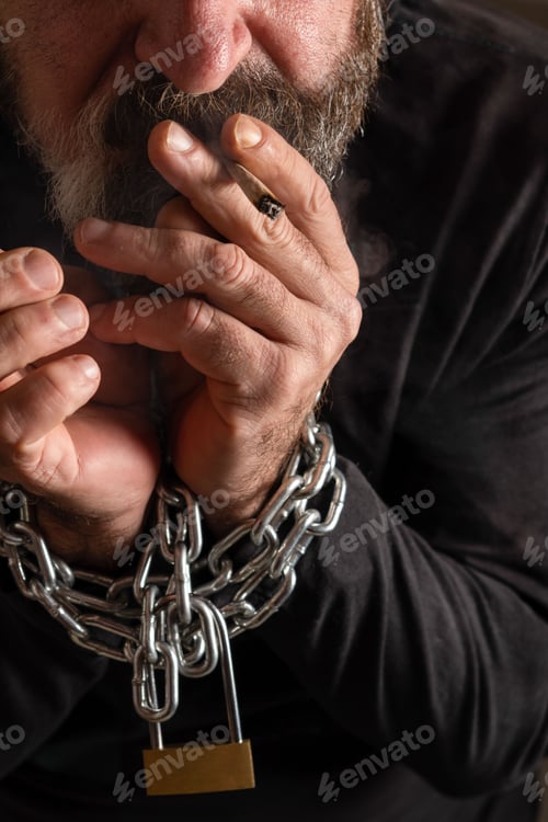 Preview: man with a cigarette in his mouth and his hands in chains,addiction concept