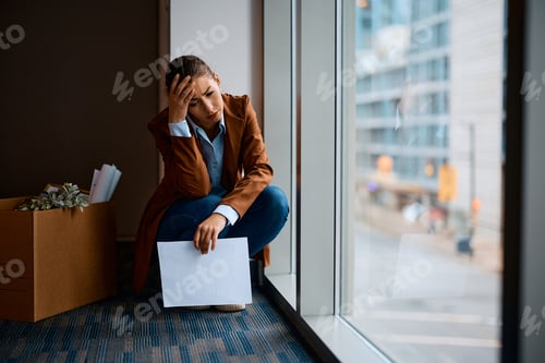 Preview: Young businesswoman feeling hopeless after being fired at work.