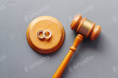 Preview: Divorce concept with gavel and wedding rings on table.