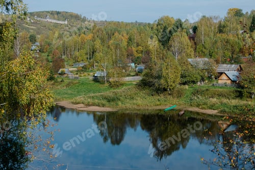 Preview: Village near river with trees and houses during daytime in autumn in rural area