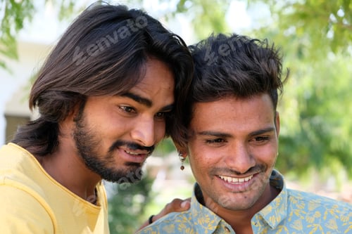 Preview: Positive Indian male friends looking at something and smiling in a park