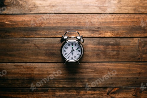 Preview: Mechanical alarm clock lying on wooden tabletop