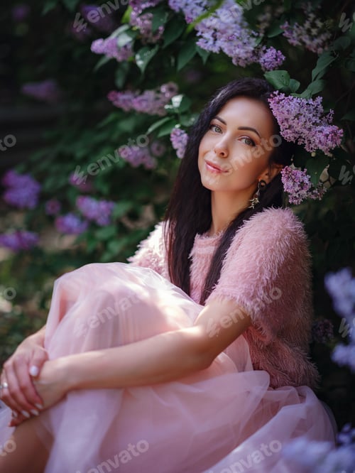 Preview: a young woman walking in a spring lilac garden